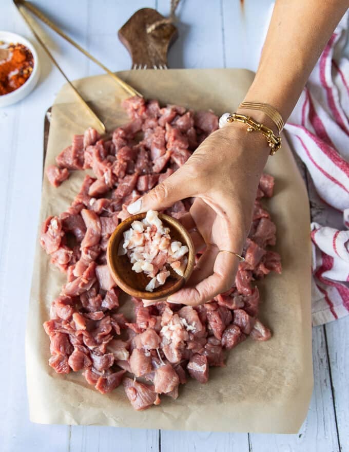 finely diced deboned lamb leg on a cutting board and the lamb fat reserved in a separate bowl 