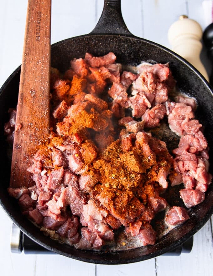 The diced meat and spices added to the hot skillet all together 