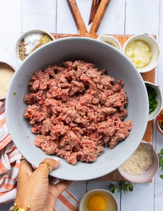 A hand holding a bowl with minced meat