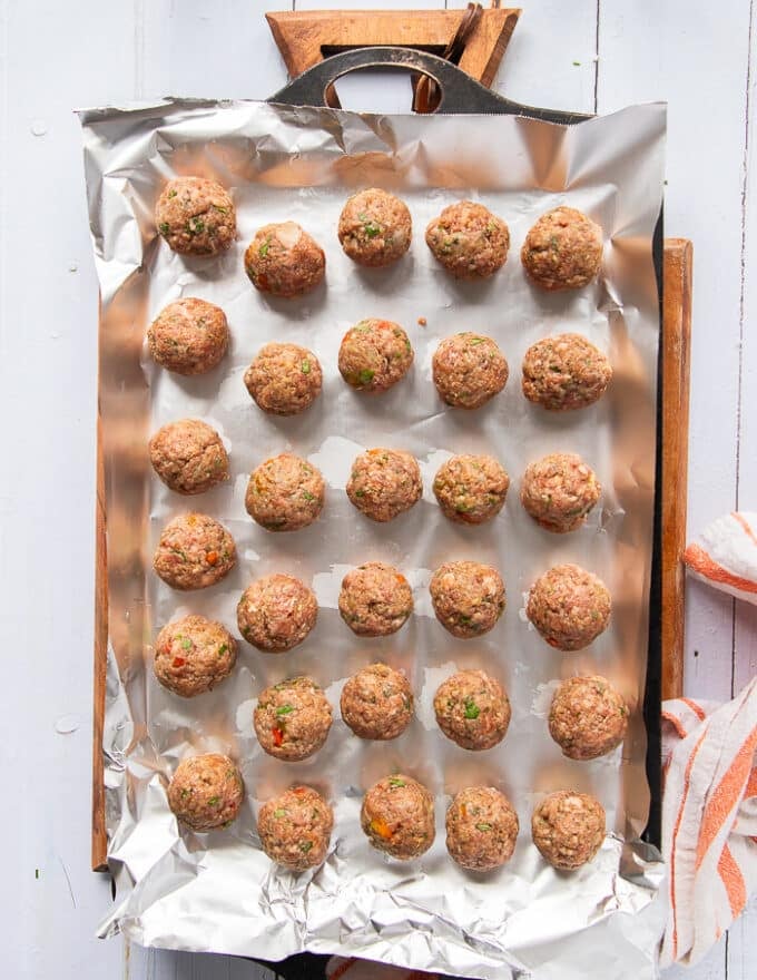 scooped up meatballs shaped into perfect meatball shape on a sheet pan