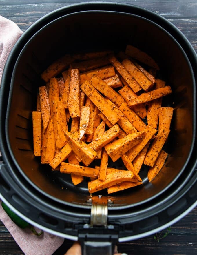 The sweet potato fries are added into the basket of the air fryer and ready to cook