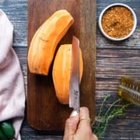 A hand cutting the sweet potatoes into half