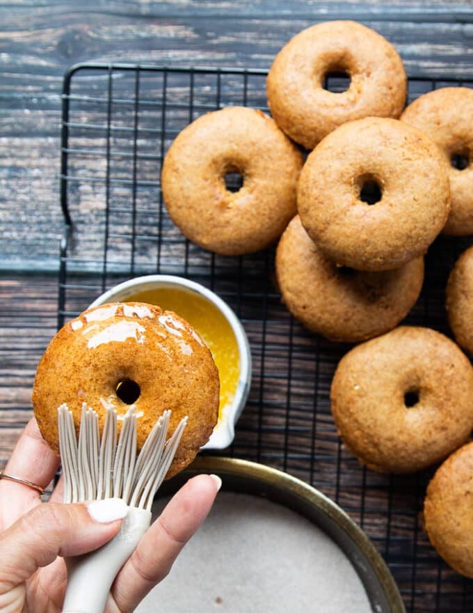 a hand brushing the donut with melted butter