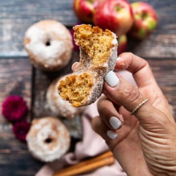 a hand holding one bit off donut to show how fluffy and soft the donut recipe is