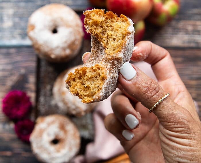 a hand holding one bit off donut to show how fluffy and soft the donut recipe is