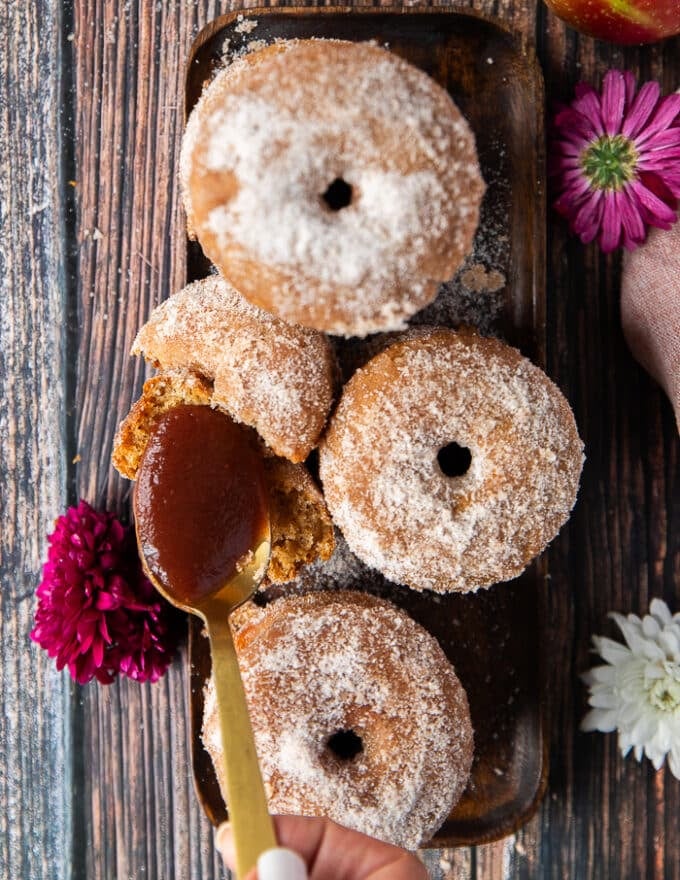 a spoon spreading some apple butter over the donuts