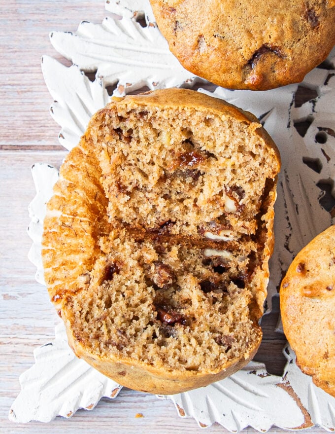 One banana bread muffin sliced in half showing the PERFECT fluffy moist texture inside studded with chocolate chunks and nuts