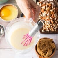 A hand holding some cream cheese glaze ready ahead of time.