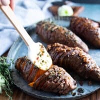 Cooked hasselback sweet potatoes out of the oven or air fryer and drizzled with extra butter sauce on top