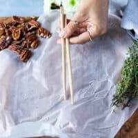 A hand holding two chopsticks over the cutting board