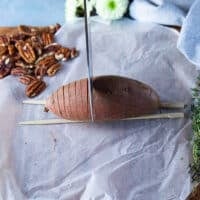 A sharp knife cutting through thin slices of the sweet potato
