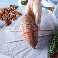 A hand showing the finished sliced hasselback sweet potato and how it should look