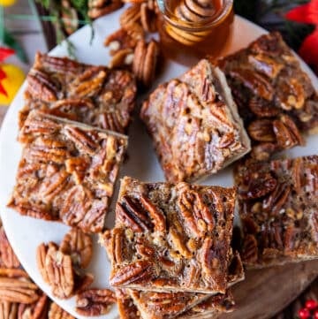 Pecan pie bars stacked on a white marble and a top view show close up of one pecan pie bar with the pecans arranged