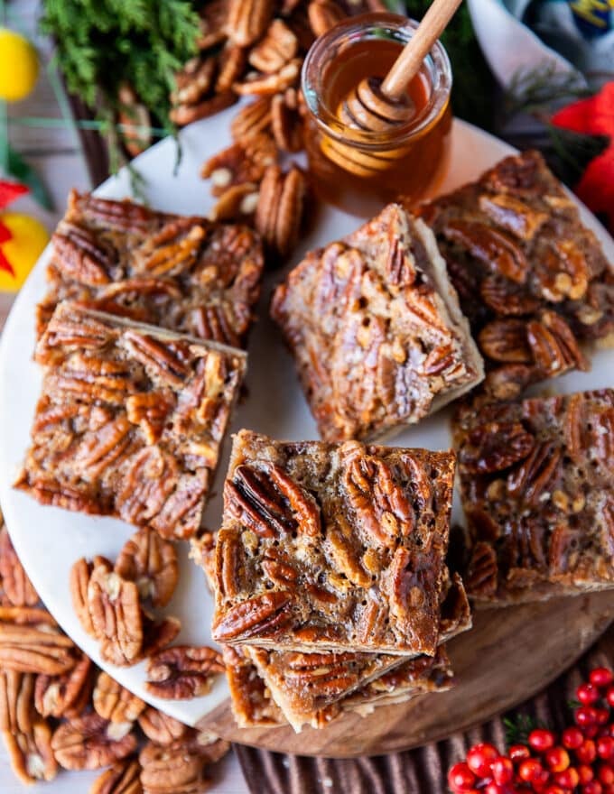 Pecan pie bars stacked on a white marble and a top view show close up of one pecan pie bar with the pecans arranged
