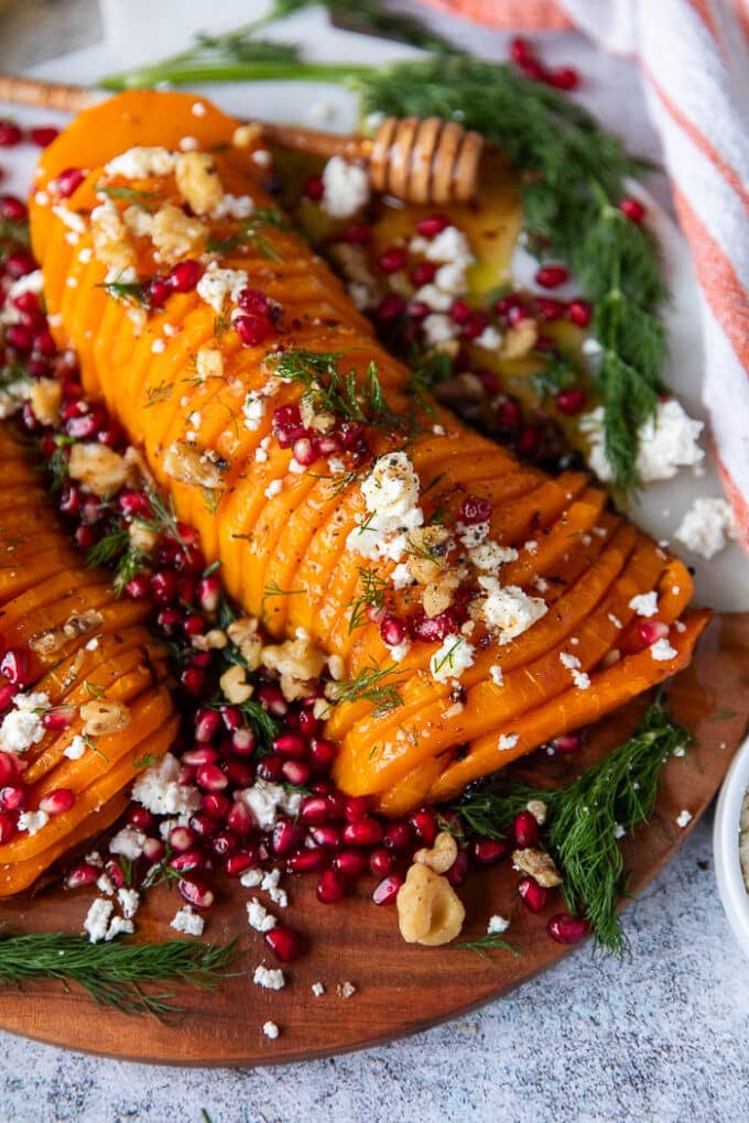 close up of a roasted butternut squash topped with feta, cranberries and walnuts