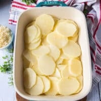 scalloped potatoes layering begins with half of the sliced potatoes at the bottom of a 9 by 13 inch baking dish