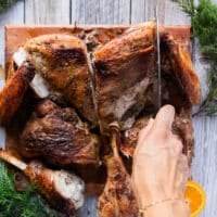 A hand separating the wings from the breast to complete carving out the turkey recipe