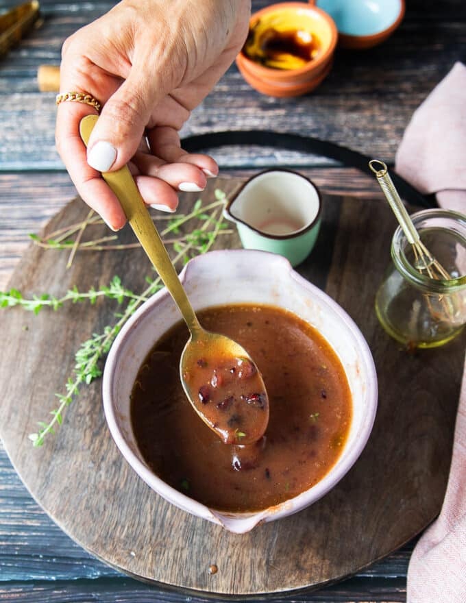 A bowl with the finished salad dressing and a hand holding a spoon to show the consistency of the salad dressing 