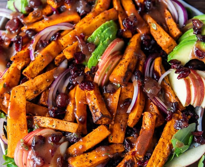 Sweet potato salad all dressed up on a plate with avocados, cooked wild rice, sweet potatoes, apples,onions and cranberries