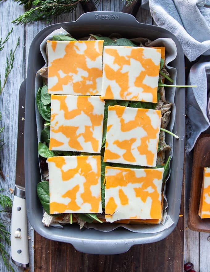 A top layer of cheese is added over the spinach to complete the turkey slider recipe layering