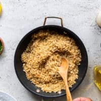 The crispy bread crumb coating is toasted and golden in the skillet with a hand tossing it, and ready to cool down