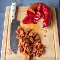 Spicy Turkish sausage cut up into small dices on a wooden board similar to bacon.