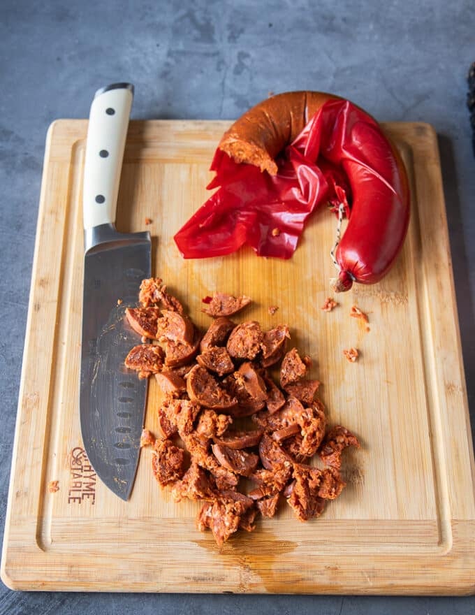 Spicy Turkish sausage cut up into small dices on a wooden board similar to bacon.