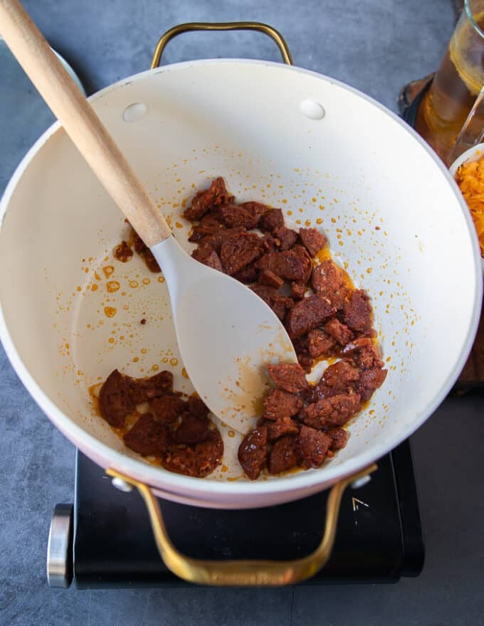 The spicy sausage or bacon is cooked in the soup pot at first until it is crispy and crumbly and cooked through