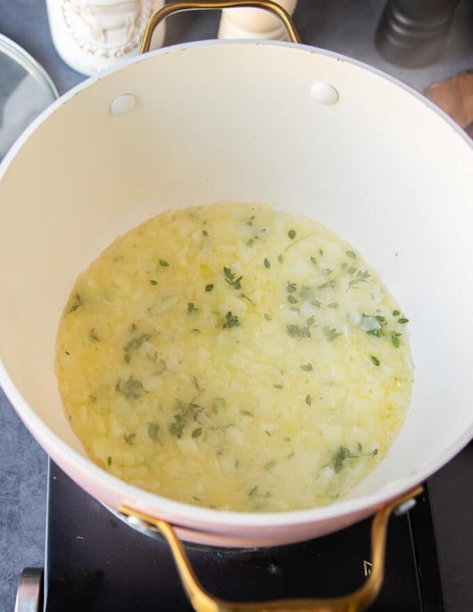 Onions and garlic sauteeing in butter with fresh thyme to make the soup base