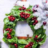 optional way of serving for the holidays-- a wreath made by fresh baby spinach leaves in a round shape, and then some fresh cranberries dotted aver the wreath to make it look super festive and placed over a round white marble