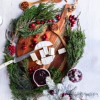 A hand using a knife to cut up cubes of brie cheese