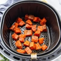 The salmon bites added to the air fryer basket in a single layer