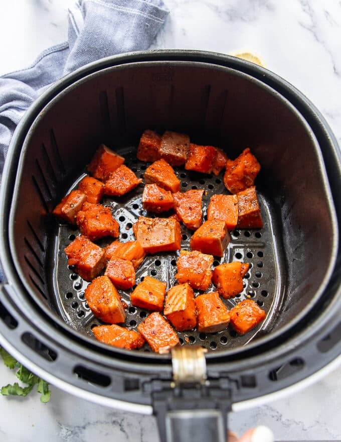 The salmon bites added to the air fryer basket in a single layer