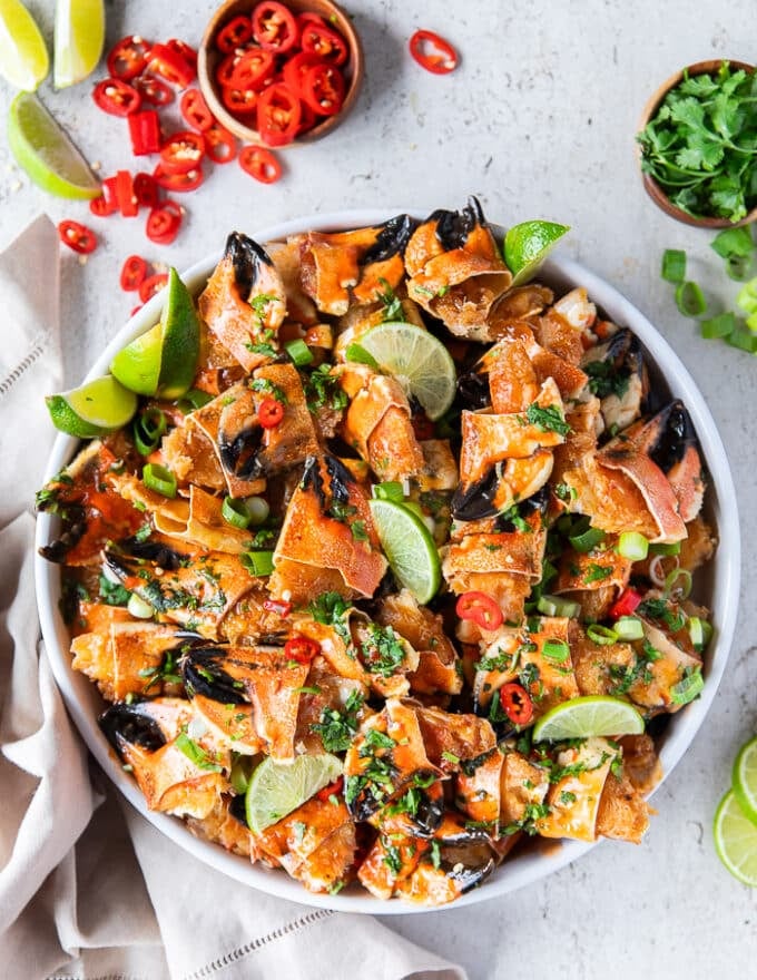 A final plate of the cooked crab claws garnished with extra cilantro and chillies, some lime wedges and surrounded by crusty bread and some melted butter