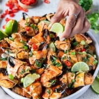 A hand squirting lime juice over a plate of cooked crab claws