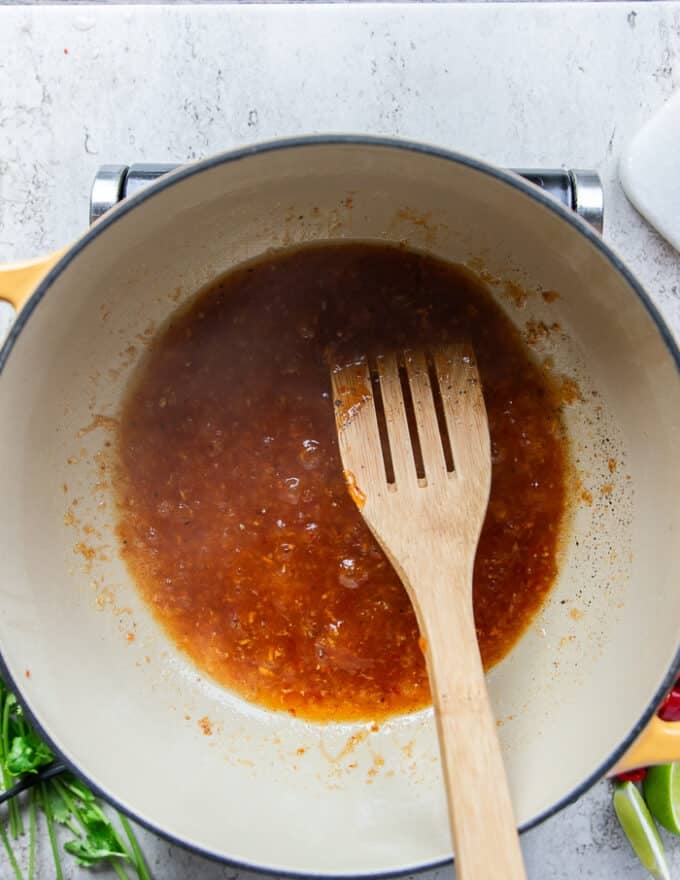 Seasoning and the sweet chilli sauce is added to the garlic in the pot