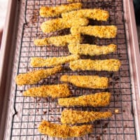 Golden and ready fish fingers right out of the oven on the cooling rack on a baking sheet