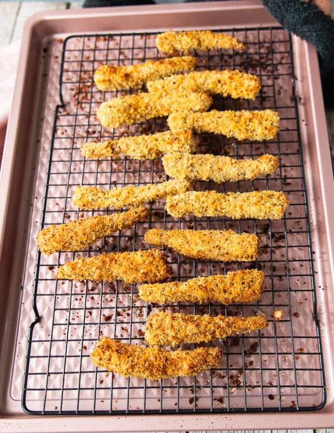 Golden and ready fish fingers right out of the oven on the cooling rack on a baking sheet