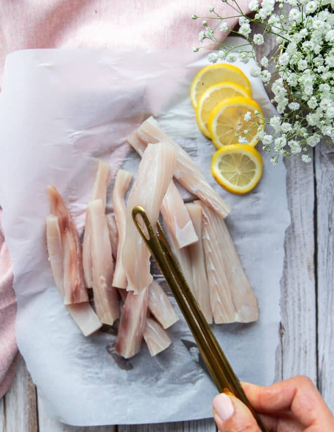 A hand holding cut up mahi mahi fish into fish fingers shape