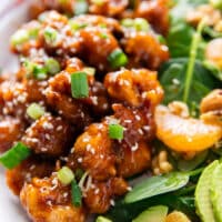 close up of the orange chicken served sprinkled with some sesame seeds and green onions chopped