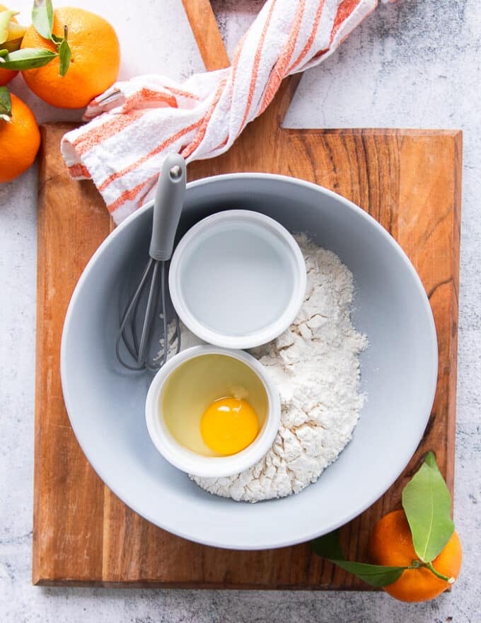 Coating ingredients for the orange chicken including a bowl of flour, a bowl of eggs, a bowl of water, a bowl of cornstarch