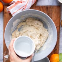 preparing the batter to coat the chicken: in a large bowl a hand is mixing the coating ingredients : the flour, seasoning, egg and water