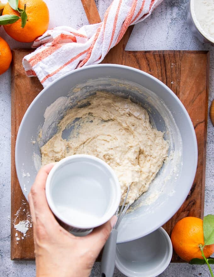 preparing the batter to coat the chicken: in a large bowl a hand is mixing the coating ingredients : the flour, seasoning, egg and water 