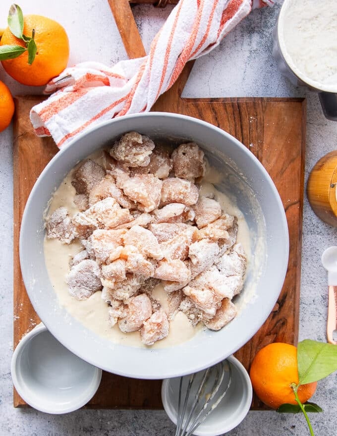 The cut up chicken chunks in a bowl tossed with some cornstarch to help stick to the batter