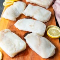 cod fish on a wooden board seasoned lightly with salt and pepper on both sides