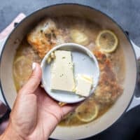 A hand holding a plate of cold butter pieces ready to add it into the sauce