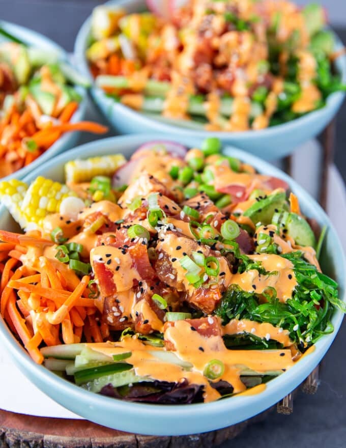 A side view of a poke bowl ready and dressed up with spicy mayo