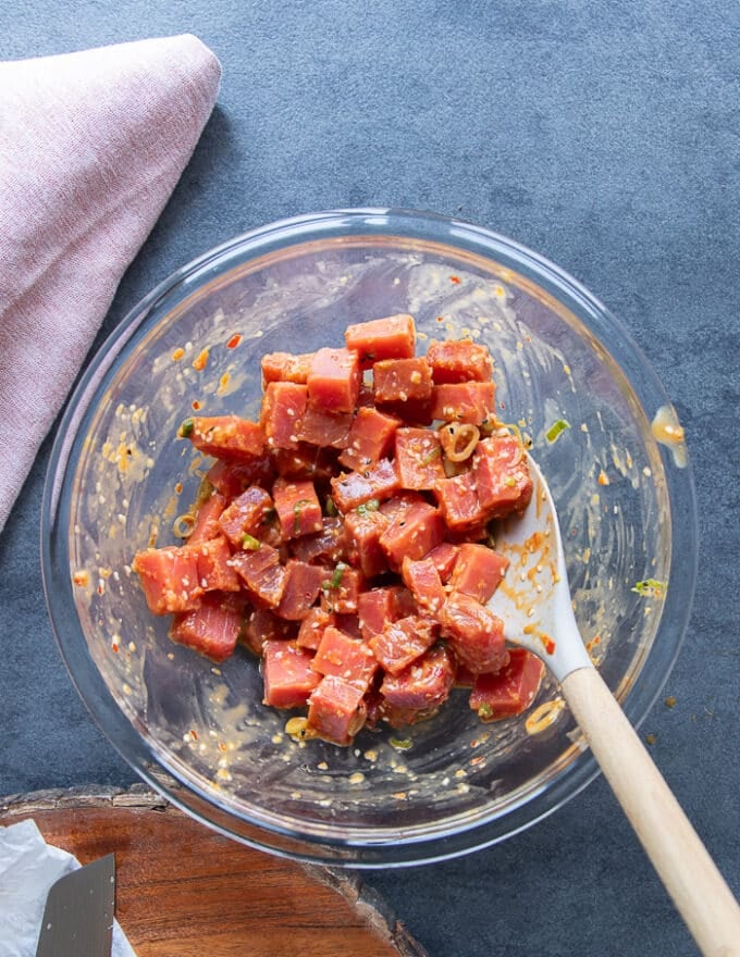 The fresh ahi tuna or saku tuna added into the bowl of seasoning and tossed using a spatula 