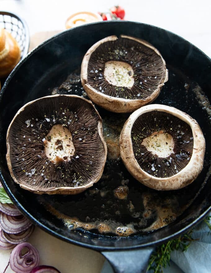 seasoned portobello mushrooms on a grill tops side down 