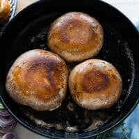 Golden and cooked tops of the mushrooms flipped to the other side to continue cooking